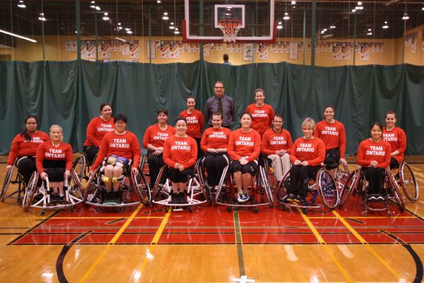 Women's wheelchair basketball team posing on court for group photo