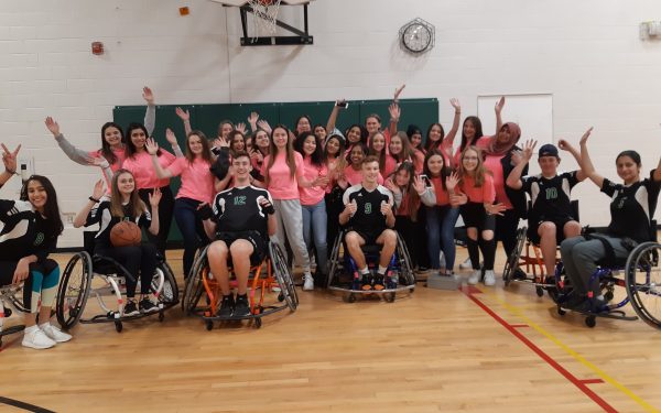 Group of students, half standing and half sitting in sport wheelchairs.