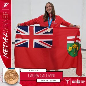 A young woman holds the Ontario flag and wears a bronze medal around her neck